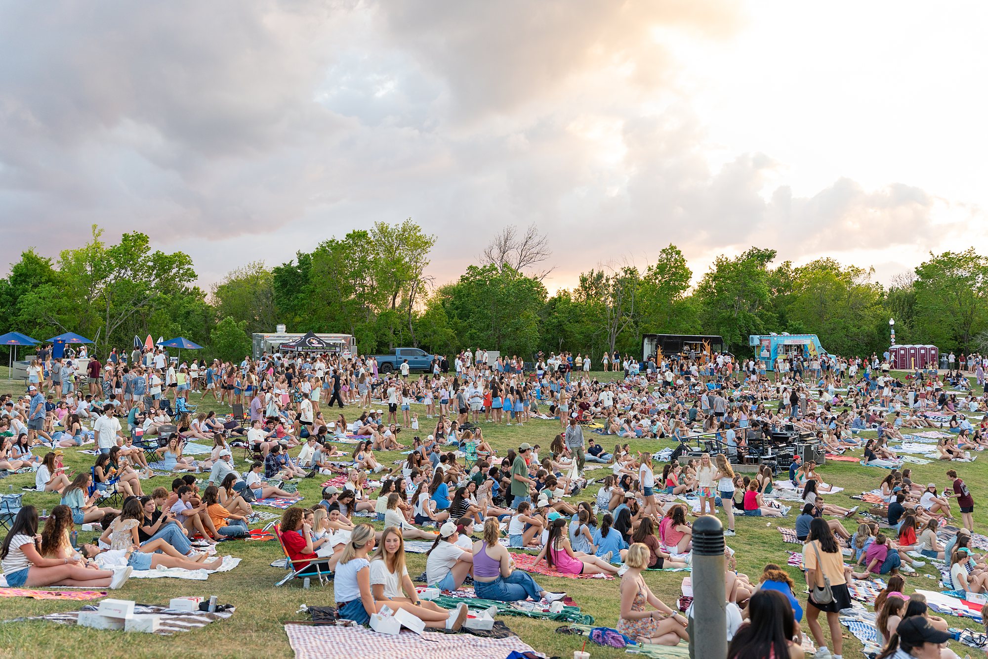 Festival crowd spread across the lawn at sunset